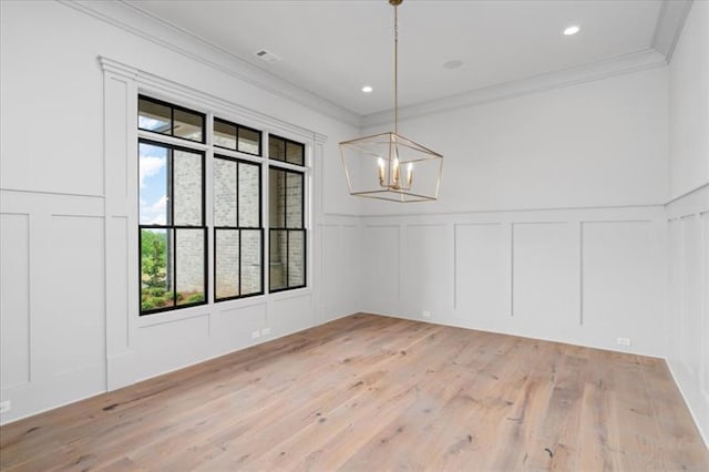 unfurnished dining area with crown molding, light hardwood / wood-style floors, and an inviting chandelier