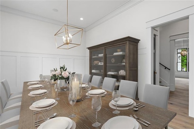 dining room with light wood-type flooring, an inviting chandelier, and ornamental molding