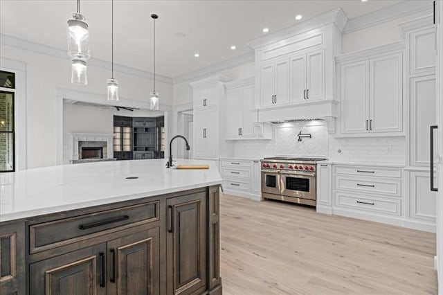 kitchen featuring white cabinetry, sink, hanging light fixtures, tasteful backsplash, and range with two ovens