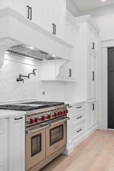 kitchen with backsplash, white cabinetry, double oven range, and light hardwood / wood-style floors