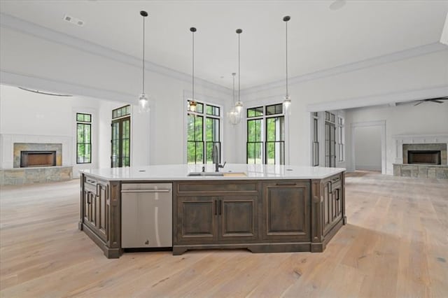 kitchen with dishwasher, a fireplace, and an island with sink