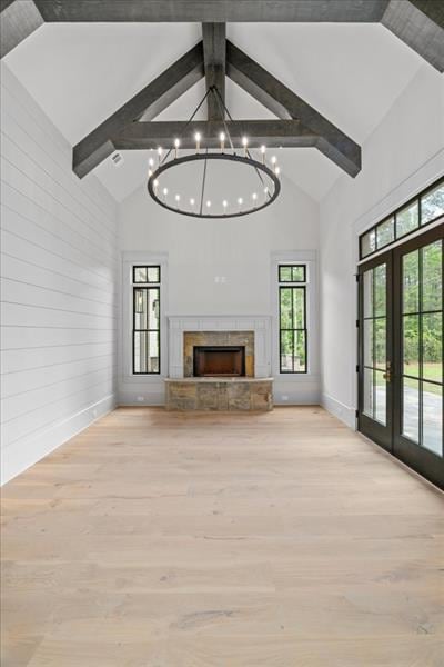 unfurnished living room featuring light hardwood / wood-style flooring, high vaulted ceiling, and a tiled fireplace