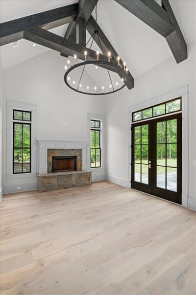 unfurnished living room with french doors, an inviting chandelier, high vaulted ceiling, beamed ceiling, and light wood-type flooring