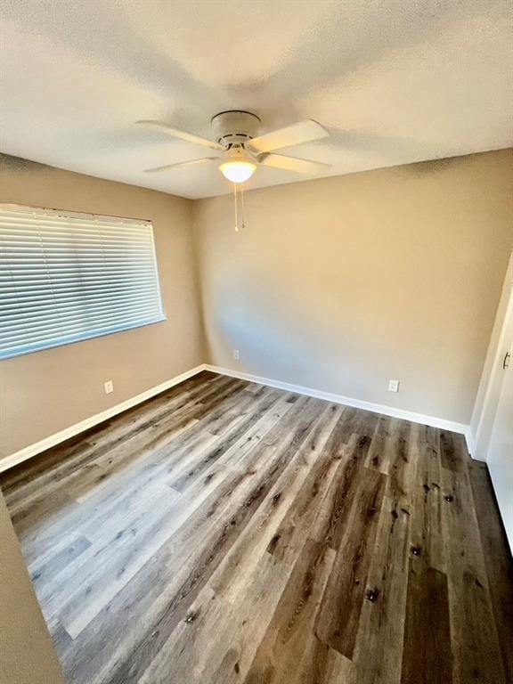 empty room with a textured ceiling, ceiling fan, and dark hardwood / wood-style floors