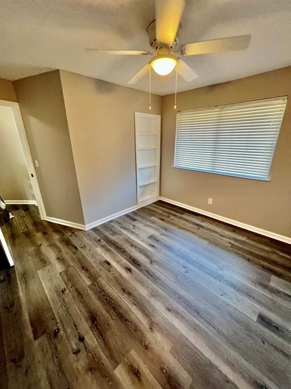 unfurnished bedroom with ceiling fan, dark hardwood / wood-style floors, a textured ceiling, and a closet