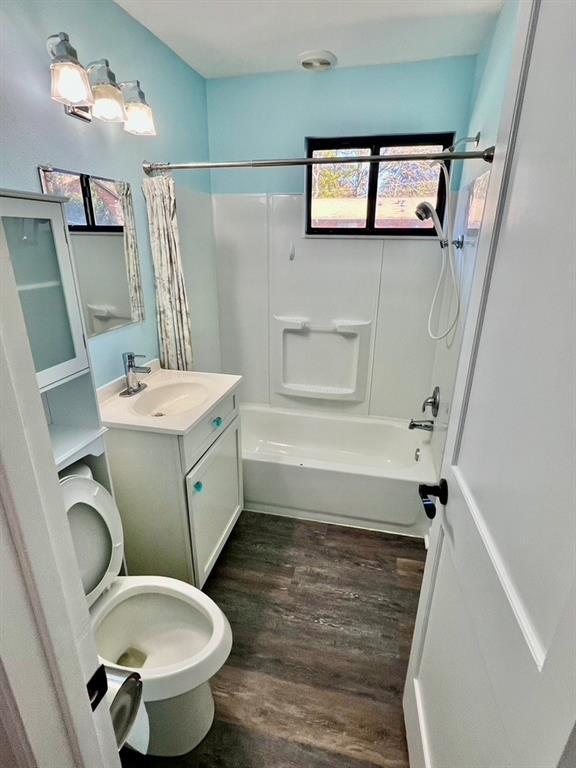 full bathroom featuring vanity, shower / bathtub combination with curtain, wood-type flooring, and toilet