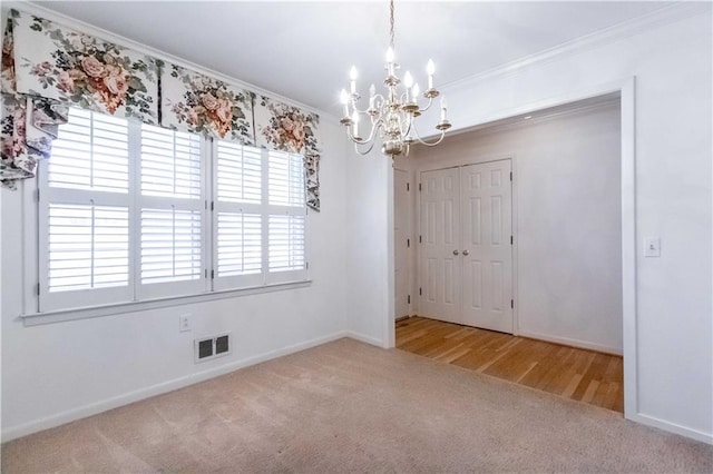 carpeted empty room with a notable chandelier and ornamental molding