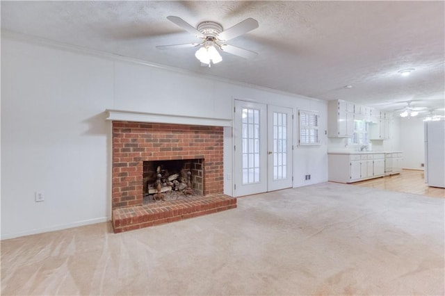 unfurnished living room featuring light carpet, french doors, crown molding, a textured ceiling, and a fireplace