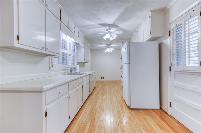 kitchen with white cabinetry, a healthy amount of sunlight, white appliances, and light hardwood / wood-style floors