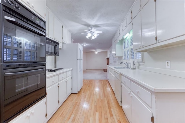 kitchen featuring white cabinetry, ceiling fan, sink, light hardwood / wood-style flooring, and black appliances