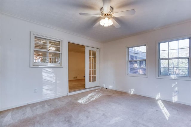 carpeted empty room featuring ceiling fan, ornamental molding, and french doors