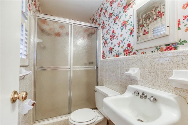 bathroom featuring sink, an enclosed shower, tile walls, and toilet