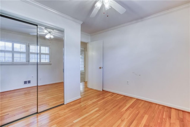 unfurnished bedroom featuring a closet, light hardwood / wood-style flooring, ceiling fan, and crown molding