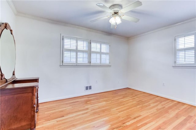 empty room featuring a wealth of natural light, crown molding, ceiling fan, and light hardwood / wood-style floors