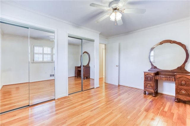 unfurnished bedroom with ceiling fan, two closets, crown molding, and light hardwood / wood-style flooring