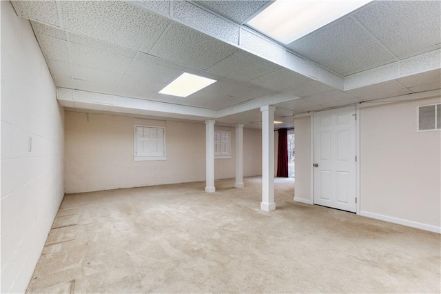 basement featuring a paneled ceiling and light carpet