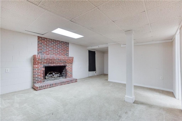 basement with carpet flooring, a paneled ceiling, and a brick fireplace