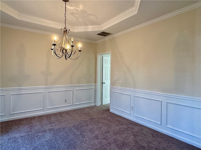 carpeted empty room featuring ornamental molding, a raised ceiling, and a chandelier