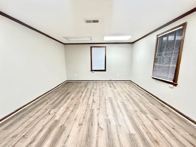 spare room featuring light wood-type flooring and crown molding