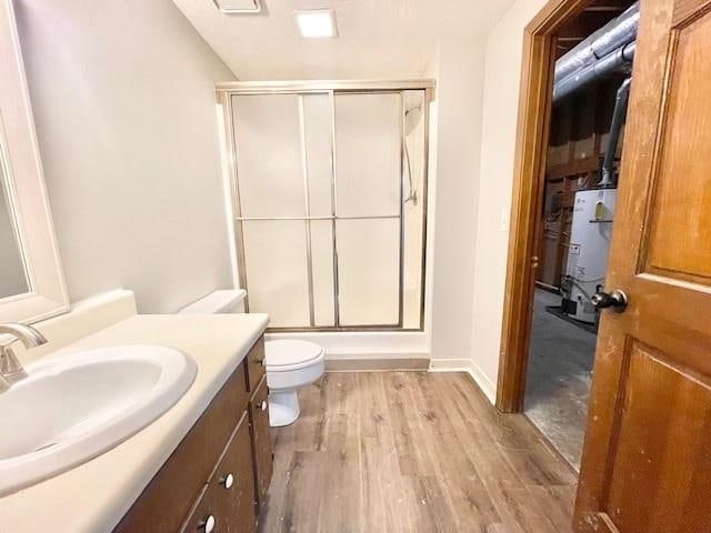 bathroom with vanity, strapped water heater, toilet, and hardwood / wood-style flooring