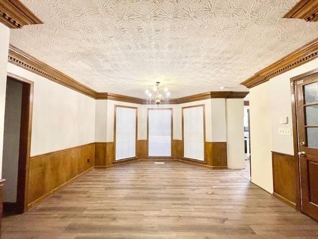 unfurnished room with a textured ceiling, crown molding, and light hardwood / wood-style flooring