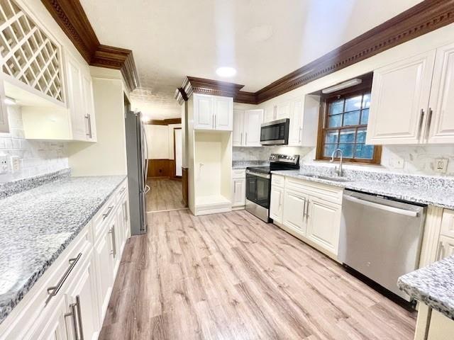 kitchen featuring sink, white cabinetry, stainless steel appliances, light stone countertops, and light hardwood / wood-style floors