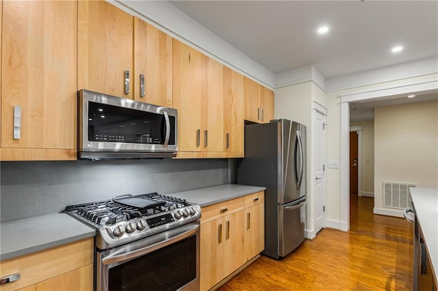 kitchen featuring light brown cabinetry, visible vents, appliances with stainless steel finishes, and light wood-type flooring