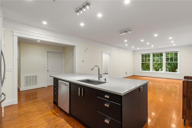 kitchen with visible vents, a sink, stainless steel dishwasher, light wood-style floors, and light countertops