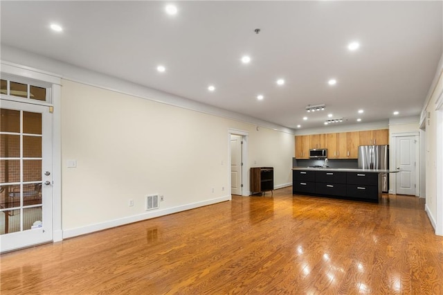 kitchen featuring a kitchen island, open floor plan, appliances with stainless steel finishes, wood finished floors, and dark cabinets