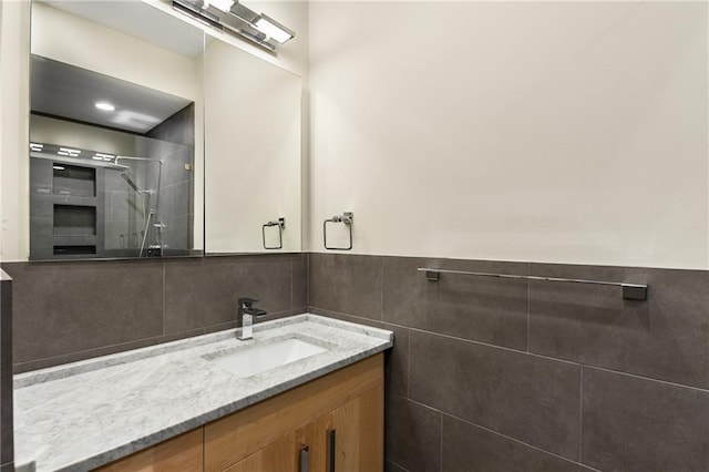 bathroom featuring wainscoting, a shower stall, vanity, and tile walls