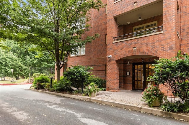 entrance to property with brick siding and a balcony