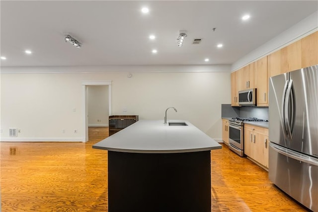 kitchen featuring a sink, appliances with stainless steel finishes, light wood-style flooring, and light brown cabinetry