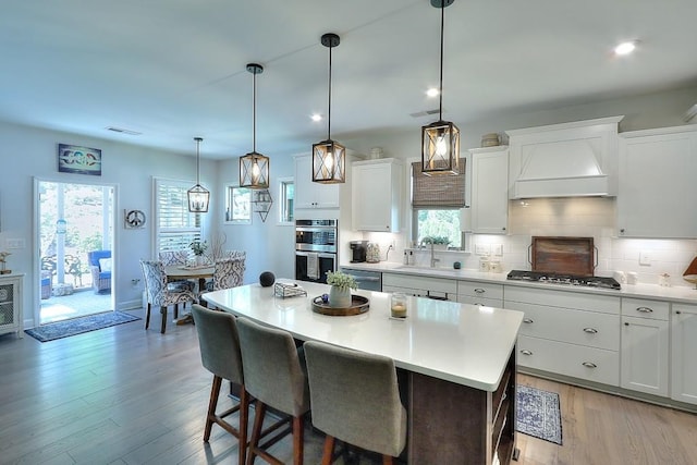 kitchen with visible vents, appliances with stainless steel finishes, a sink, premium range hood, and backsplash