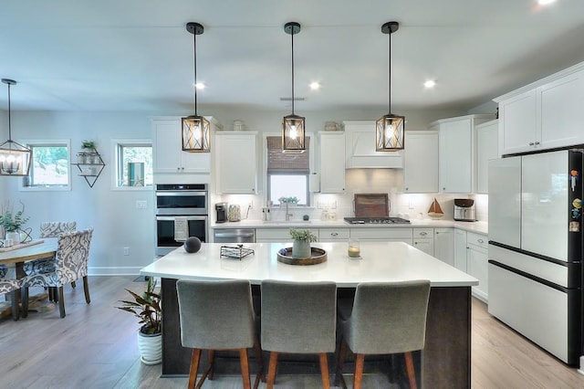 kitchen with stainless steel appliances, light countertops, a sink, and backsplash