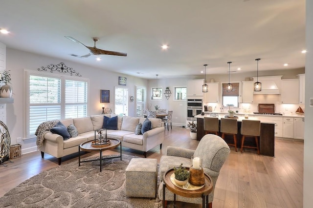 living area featuring light wood-style flooring, baseboards, ceiling fan, and recessed lighting