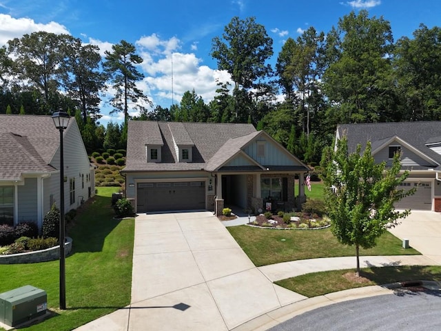 view of front facade with board and batten siding, a front yard, roof with shingles, and driveway