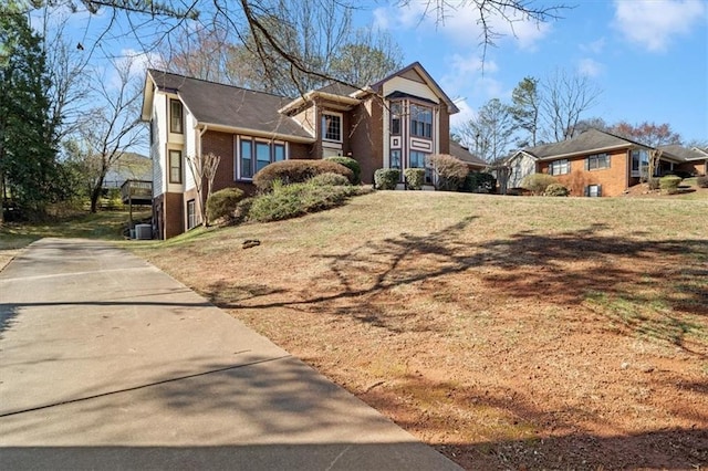 traditional-style house featuring brick siding, cooling unit, and a front yard