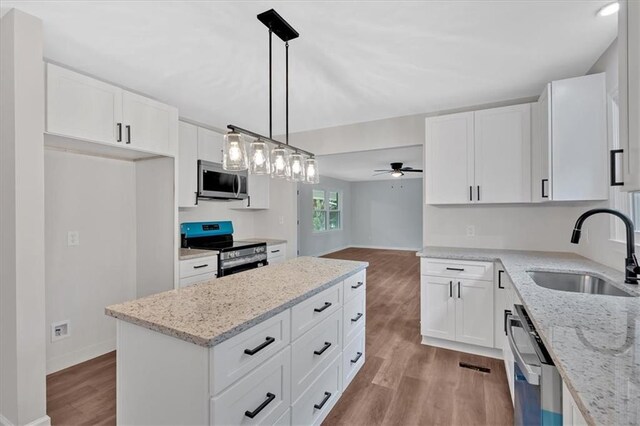 4477 Timber Ridge Dr, Douglasville, GA 30135 - kitchen with appliances with stainless steel finishes, light wood-type flooring, ceiling fan, a kitchen island, and white cabinetry