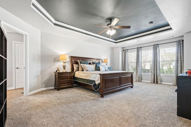 carpeted bedroom with a tray ceiling and ceiling fan