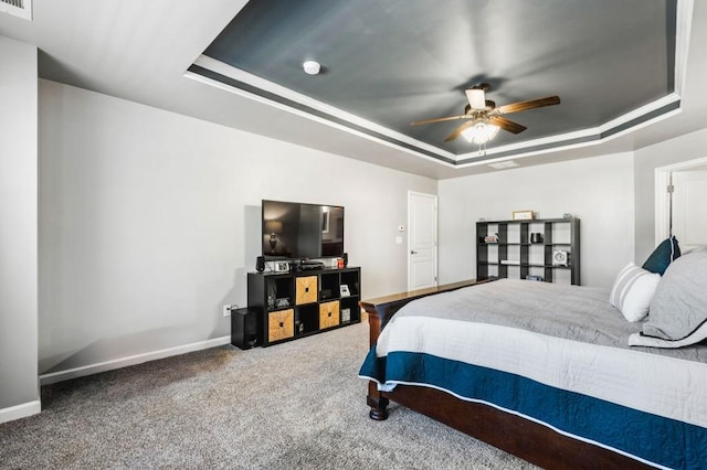 carpeted bedroom featuring ceiling fan and a tray ceiling