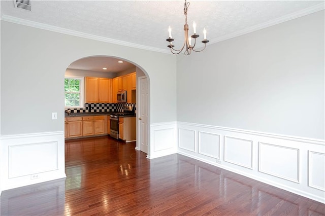 spare room with dark hardwood / wood-style floors, an inviting chandelier, ornamental molding, and a textured ceiling