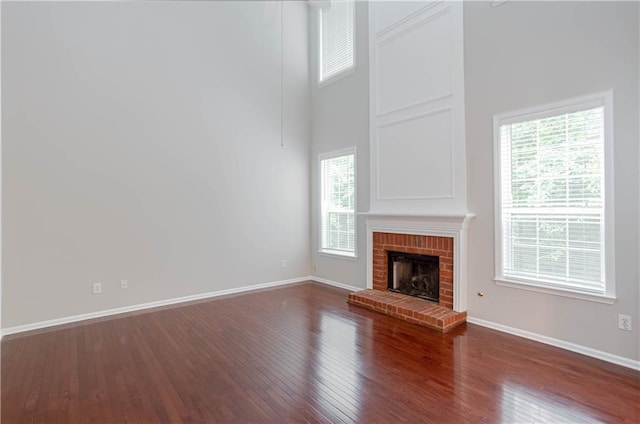 unfurnished living room featuring dark hardwood / wood-style floors, a towering ceiling, and a fireplace