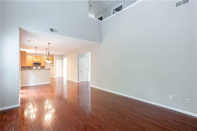 empty room featuring a high ceiling and dark hardwood / wood-style flooring