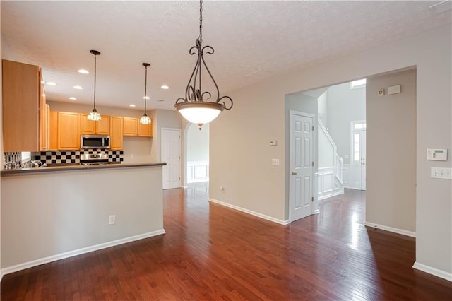 kitchen featuring light brown cabinets, decorative light fixtures, a healthy amount of sunlight, backsplash, and dark hardwood / wood-style floors