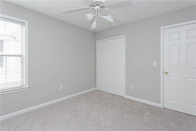 unfurnished bedroom with a closet, light colored carpet, and ceiling fan