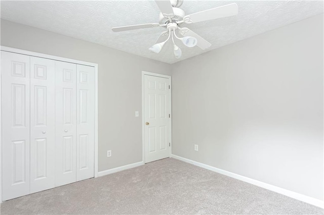 unfurnished bedroom featuring ceiling fan, light carpet, and a textured ceiling