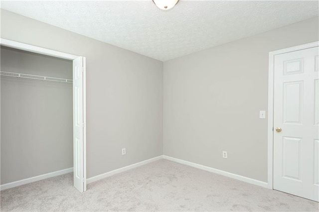 unfurnished bedroom with light colored carpet, a closet, and a textured ceiling