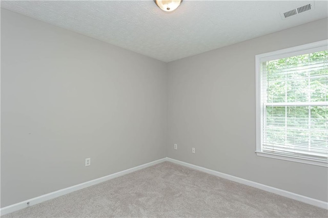 carpeted empty room featuring a textured ceiling