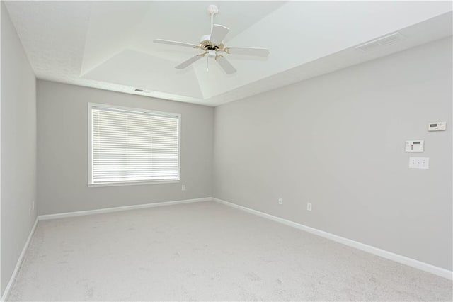 spare room featuring ceiling fan, a raised ceiling, and light carpet