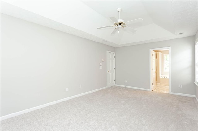 carpeted empty room featuring ceiling fan and a tray ceiling